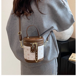 Détail d'un mini sac seau avec motifs cartoon et ferrures dorées porté par un mannequin