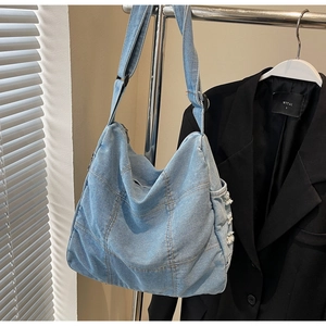Detailed view of light blue denim tote with square patchwork and frayed edge accents