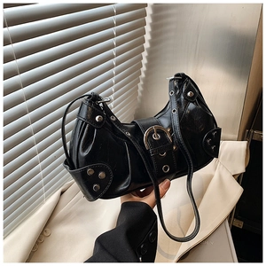 Close-up of black leather baguette bag featuring silver studs and metal buckle details