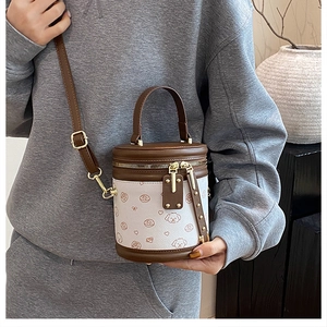 Détail du mini sac seau blanc avec motifs chiots marrons et finitions dorées chic