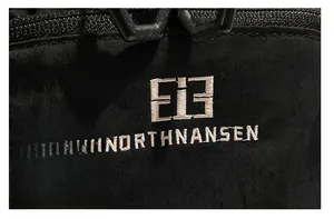 Macro shot of high-density Northnansen logo embroidery on black ripstop nylon fabric