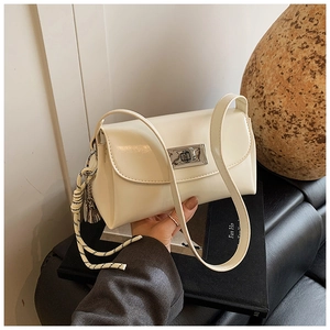 Détail du sac polochon en cuir crème avec fermoir rotatif argenté et lanière tressée chic
