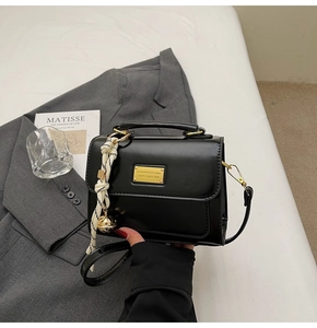 Detail of black crossbody bag with gold hardware and black and white tassel charm