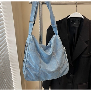 Close-up of vintage denim tote bag featuring block stitching and adjustable shoulder strap