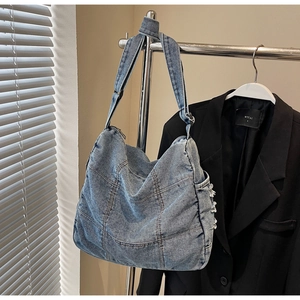 Detailed close-up of light blue quilted denim tote bag with frayed fringe and adjustable strap