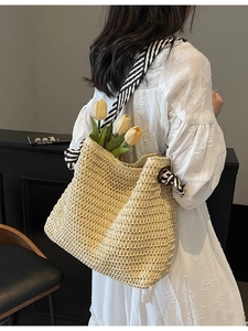 Chic beige straw woven tote bag with striped ribbon straps and floral decorative accents