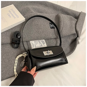 Détail du sac polochon noir brillant avec fermoir argenté et pendentif de sport