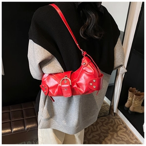 Detail of red glossy faux leather shoulder bag with silver buckles on a female model