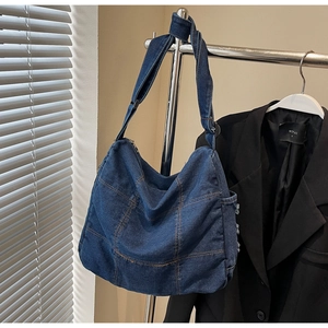 Detail of vintage denim hobo bag featuring contrast orange stitching and patchwork design
