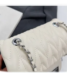 Detail of V-quilted faux leather crossbody bag with silver chain strap and metal lock