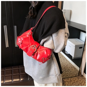 Detail of red patent leather shoulder bag with silver buckle and rivet accents