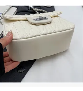 Close-up of beige quilted crossbody bag with silver chain and metal twist lock