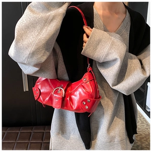 Detail of red faux leather shoulder bag with glossy finish and punk rivet accents