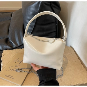 Detail of creamy white pleated pillow bag with chunky handle and silver chain strap