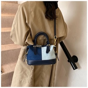 Lifestyle view of a blue denim patchwork handbag with golden hardware and leather strap