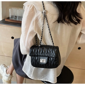 Detailed shot of black matelassé crossbody bag with silver chain strap on model