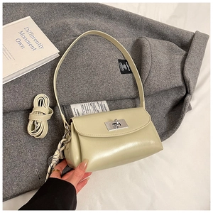 Détail d'un sac en cuir PU vert clair avec fermoir rotatif argenté sur tissu gris
