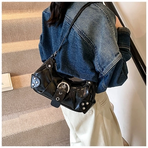 Detail of glossy black leather baguette bag featuring silver studs and metal buckle