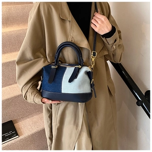 Detail of denim patchwork Boston bag with leather handles and gold-tone hardware