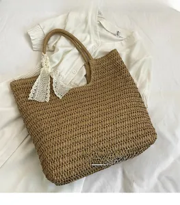 Detail of large straw tote bag featuring a white lace bow and dense woven texture