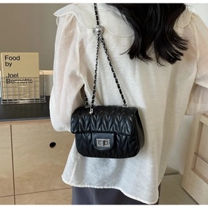 Detail of black quilted chain strap bag showing V-pattern texture and silver clasp