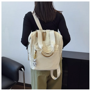 Vista trasera detallada de mochila blanco roto con elegante colgante de oso plateado