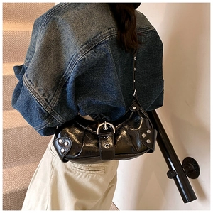 Close-up of black glossy baguette bag with silver hardware and punk-style metal rivets