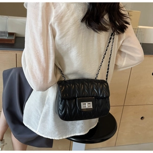 Detail of a black V-quilted crossbody bag with silver twist lock and chain strap