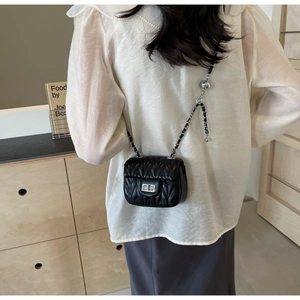 Close-up of black V-quilted mini chain bag with silver twist lock and leather strap