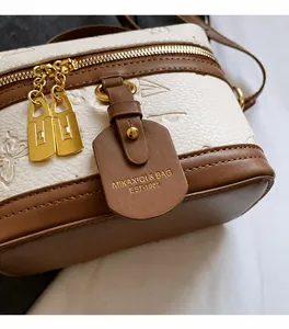 Detail view of contrast color crossbody bag with gold hardware and pebbled leather texture