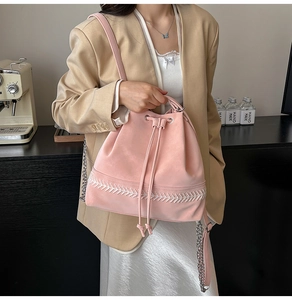 Dettaglio della borsa a secchiello rosa con coulisse, ricami bianchi e tracolla a catena