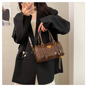 Detail of dark coffee Boston bag featuring oil wax texture and gold hardware on model