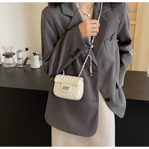 Close-up of cream quilted mini bag with silver chain strap and metal turn-lock closure