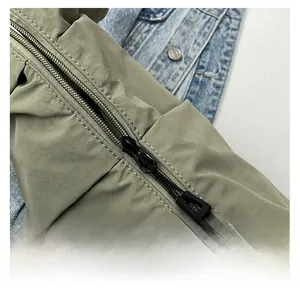 Detail shot of the olive green fabric texture and smooth black double zipper on the bag