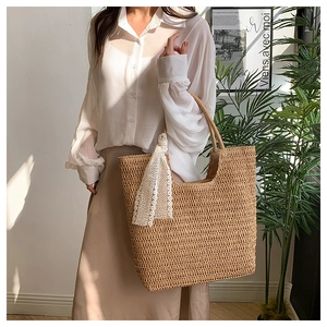 Detail of woven straw tote bag with white lace ribbon bow accent in a bright interior