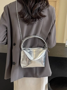 Metallic silver pillow bag with chain strap shown from a model's back view
