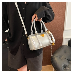 Detailed view of silver metallic Boston bag featuring gold hardware and logo plate