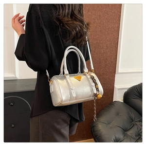 Detail of silver metallic Boston bag featuring dual handles and a signature metal triangle logo