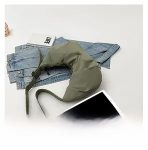 Flat lay of an olive green crescent crossbody bag with laptop and books on white background