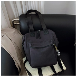 Detalle de mochila de nailon negro con colgante de oso plateado sobre fondo de estilo de vida