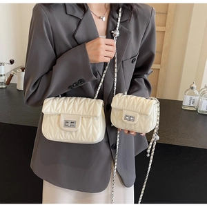 Detail of cream quilted chain bags in two sizes with silver twist-lock and chain strap