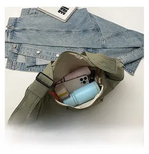 Army green crossbody bag showing large capacity with phone, bottle, and umbrella
