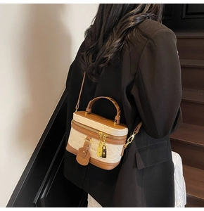 Detail of cream and brown box bag with floral relief and golden chain on model