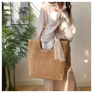 Detail der handgewebten Strohtasche mit weißem Spitzenband am Griff für den Sommer