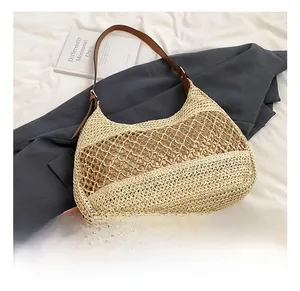 Detailed view of hollow straw tote bag with brown leather strap and woven texture
