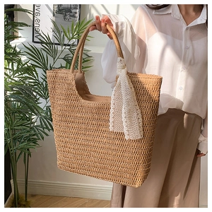 Detail view of woven straw tote bag featuring delicate hollow texture and lace scarf accent