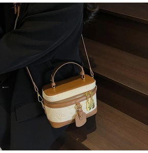 Detail of vintage box-shaped vanity bag with cream embossed pattern and brown leather trim