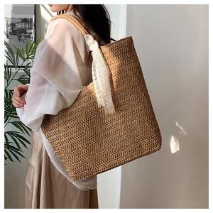 Detail of hand-woven straw tote with elegant white lace ribbon handle on shoulder