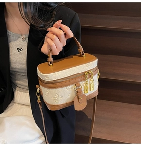 Detail of white butterfly embossed barrel bag with brown handles and gold lock pendant