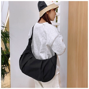 Black casual dumpling crossbody bag with natural pleats and wide strap shown on shoulder